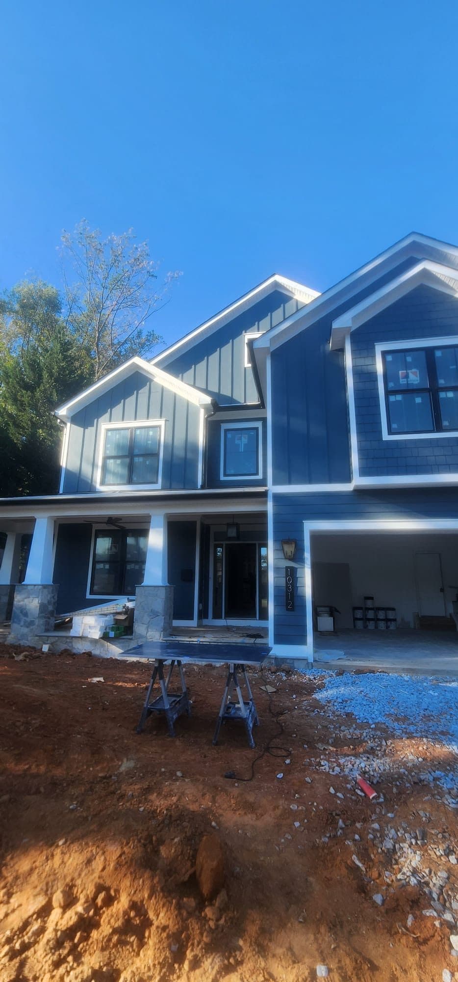 Home with finished navy blue two-tone siding, board-and-batten gable, and a covered front porch