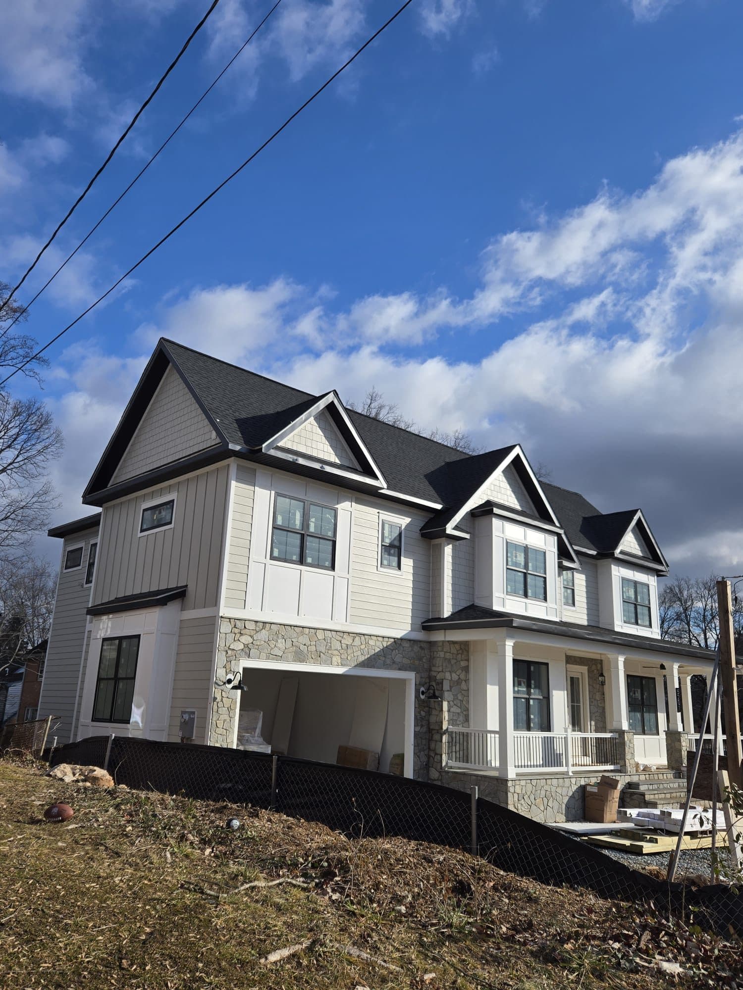 Finished home with two-tone gray siding, stone foundation, and a covered wraparound porch